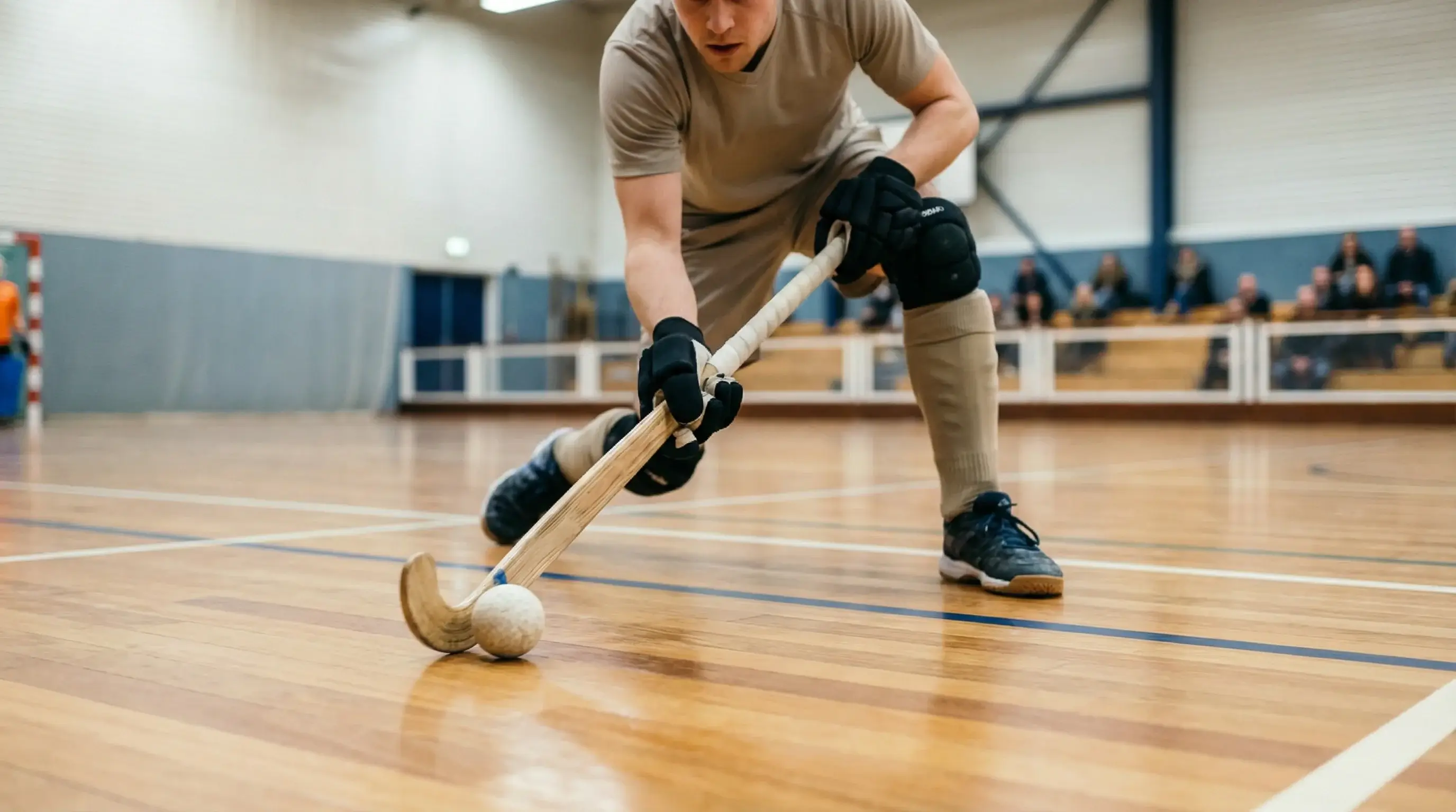 Close-up van een zaalhockeyspeler met de bal op een indoor veld